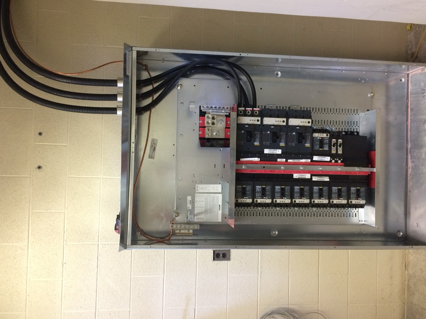 Open commercial distribution panel with copper feeders terminated at the main breakers