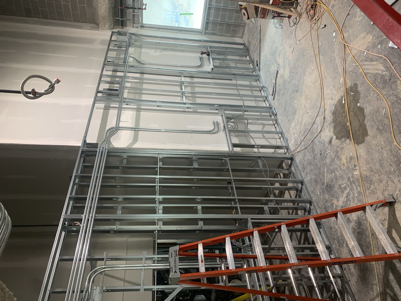 Steel stud wall framed with conduit rough-in during a commercial build-out