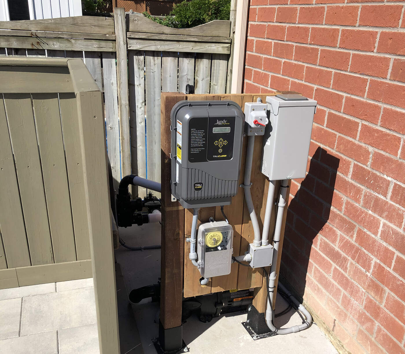 Pool salt chlorinator and electrical disconnect mounted on a backyard equipment pad