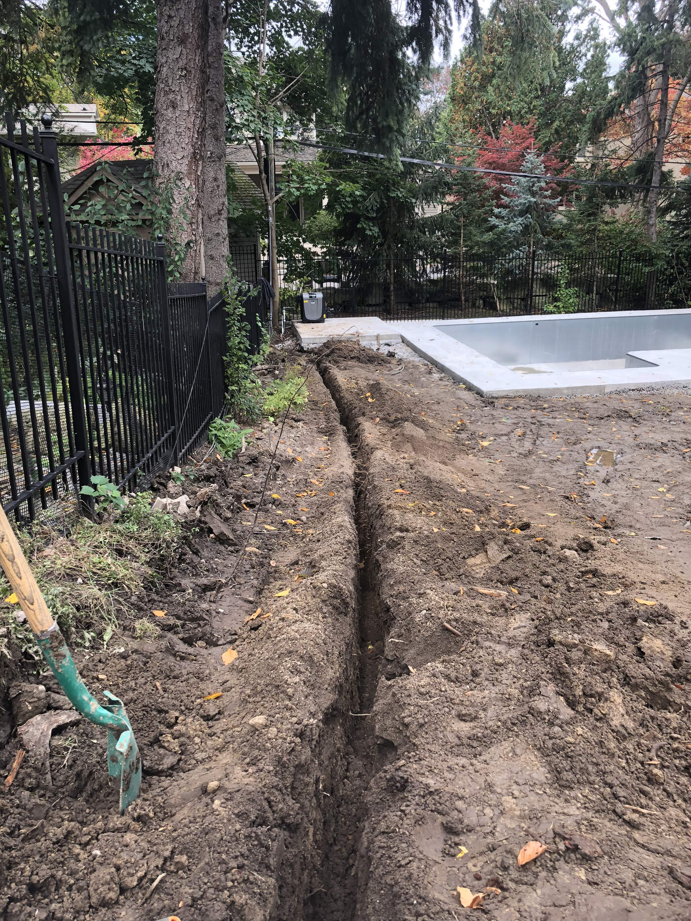 Trench dug for underground electrical service to a new backyard pool